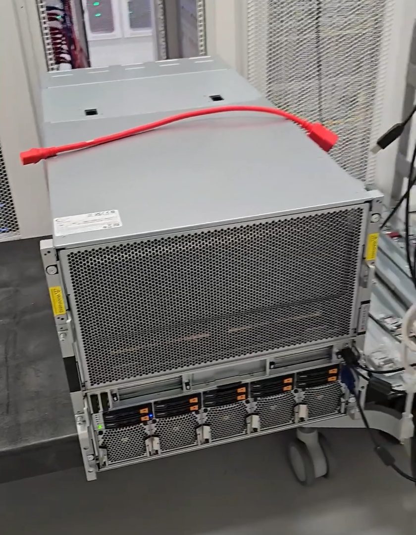 Een HGX-klasse GPU-server uit het rack op een liftkar in een datacentergang, wachtend op installatie.